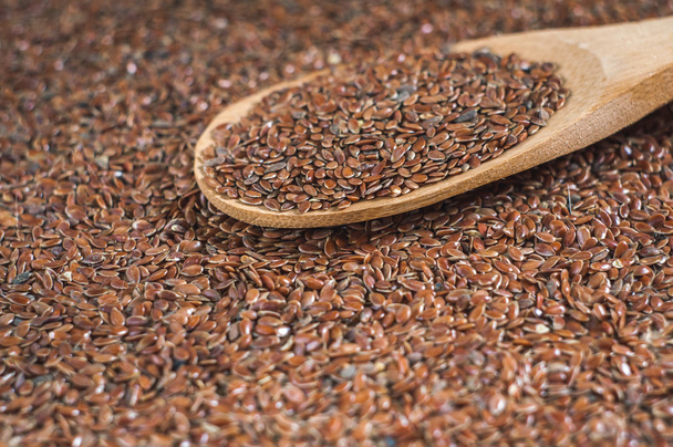 semillas de lino con una cuchara de madera sobre fondo de arpillera
 - Foto, Imagen