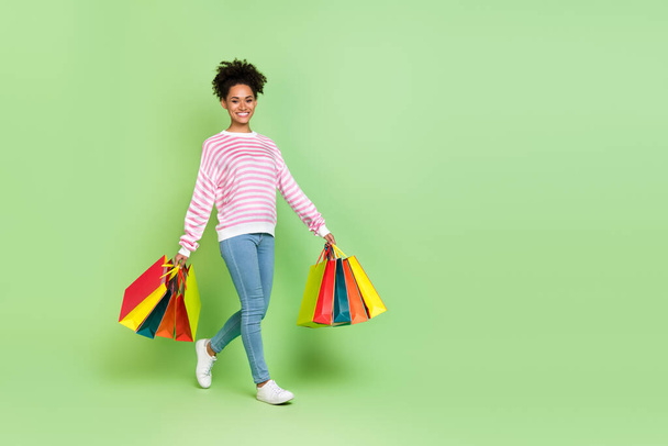 Photo of charming pretty lady hold store packages enjoy stroll wear striped shirt jeans isolated green color background. - Fotó, kép