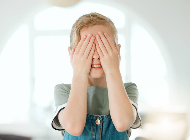 Shot of an adorable little girl standing alone at home and covering her eyes with her hands. - 写真・画像