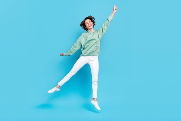 Full body photo of cool young brunette lady jump wear hoodie pants sneakers isolated on blue background. - Photo, image