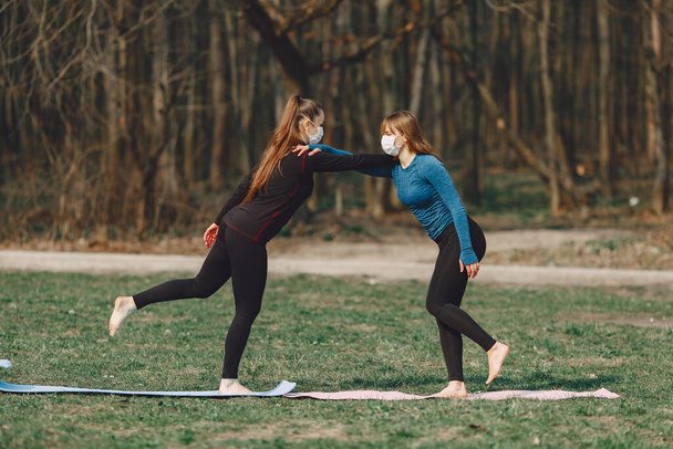 Beautiful girls training. Girls in a summer park. Lady make a yoga. Coronavirus theme - Fotoğraf, Görsel