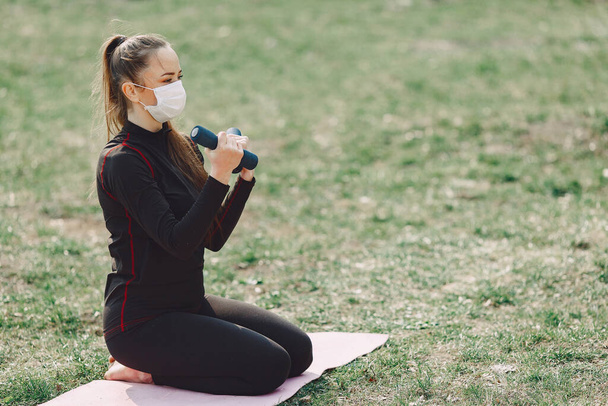 Beautiful girl training. Girl in a summer park. Lady make a yoga. Coronavirus theme - Photo, Image