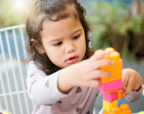 Shot van een schattig klein meisje spelen met bouwstenen buiten. - Foto, afbeelding