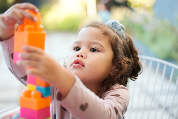 Shot of an adorable little girl playing with building blocks outside. - 写真・画像
