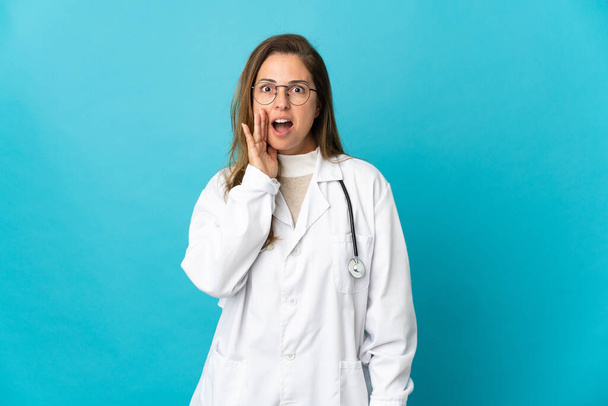 Brasilianische Ärztin mittleren Alters isoliert auf blauem Hintergrund mit Überraschung und schockiertem Gesichtsausdruck - Foto, Bild