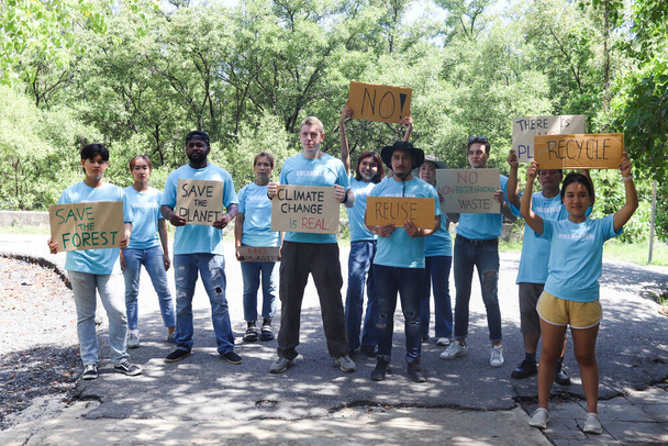 Grupa ochotników protestujących przeciwko zanieczyszczeniu ziemi i globalnemu ociepleniu, ludzie trzymają znaki protestu i wychowują je, aby motywować ludzi do pracy charytatywnej i ratować planetę, świadomi naturalnego środowiska. - Zdjęcie, obraz