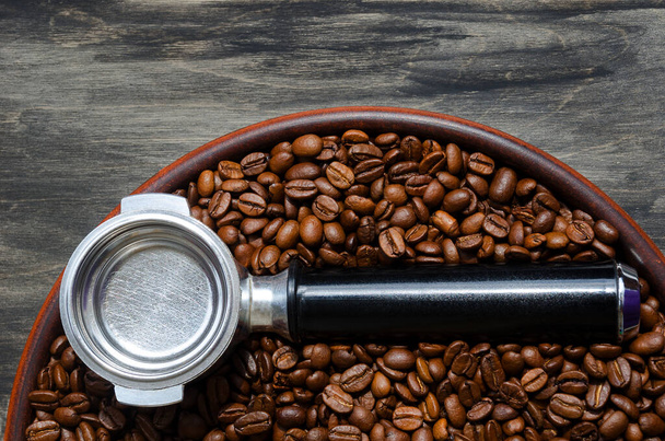 Il corno di caffè si trova su chicchi di caffè e su un piatto di ceramica. Su uno sfondo nero. - Foto, immagini