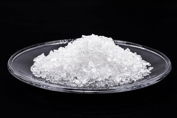 sodium chloride, known as salt or table salt, an important food preservative and a popular seasoning, isolated on black background - Photo, Image