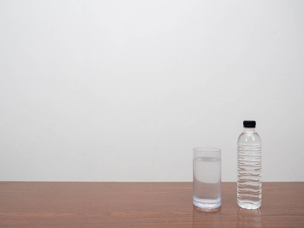 Butelka wody ze szkłem na drewnianym stole kopia przestrzeń białe tło - Zdjęcie, obraz