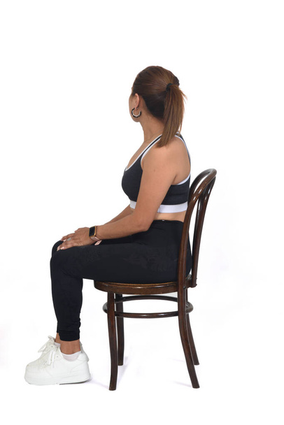 full view of a woman sitting on chair and looking backwards on white background - Fotografie, Obrázek