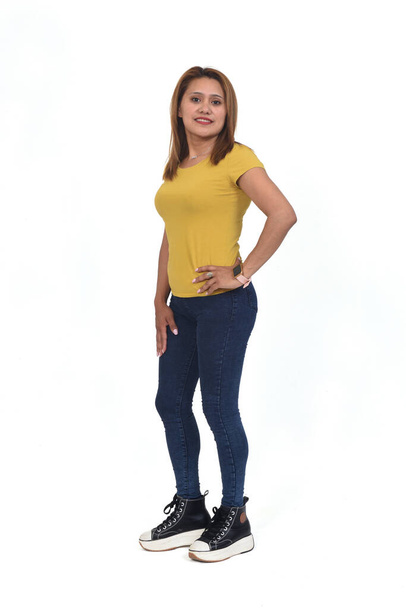 side view of woman with slim jeans looking at camera and hands on hip on white background - Photo, Image