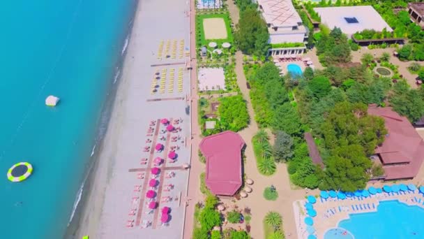 Drone vista de un hermoso complejo de playa con una piscina, sombrillas y mar turquesa. Paradise place, Georgia. - Metraje, vídeo