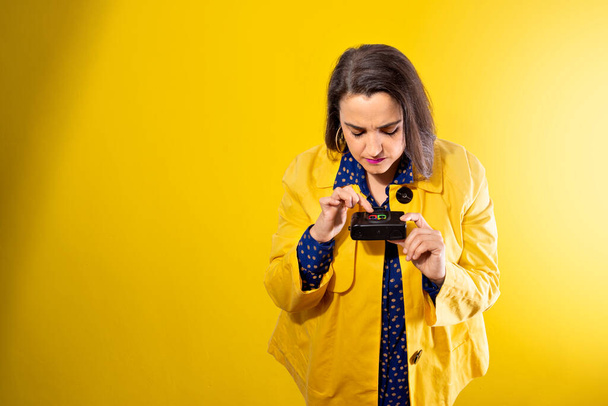 young girl on yellow background looking at a photo camera - Fotoğraf, Görsel