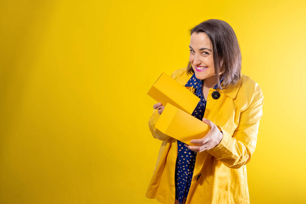young girl on yellow background uncovering a box - Foto, immagini