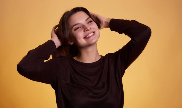 Jonge brunette vrouw in trui poseren geïsoleerd op gele achtergrond studio portret. Mensen oprecht emoties lifestyle concept. Mock up kopieerruimte. - Foto, afbeelding