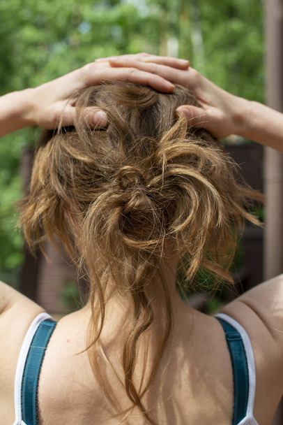 Natural unbrushed hair of a young woman in a messy up do hairstyle. Close up, back view. - Photo, Image