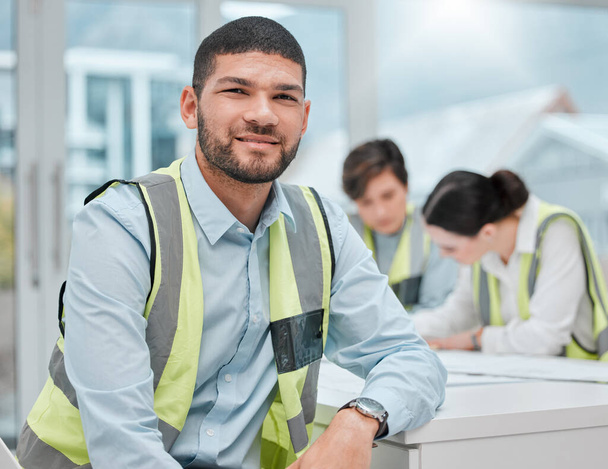 Cropped portrait of a handsome young male construction worker sitting in a meeting with his colleagues. - Photo, Image