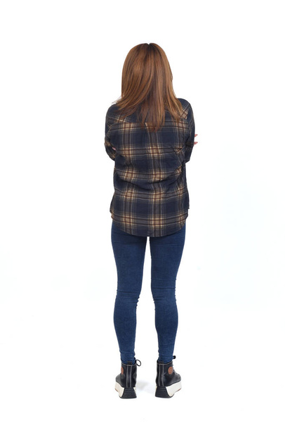 rear view of a woman with jeans and shirt, amrs crossed on white background - Photo, Image