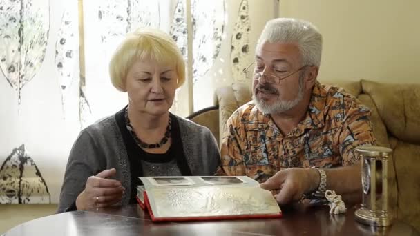 Συνταξιούχο ζευγάρι ψάχνει σε ένα άλμπουμ που είναι εσωτερική - Πλάνα, βίντεο