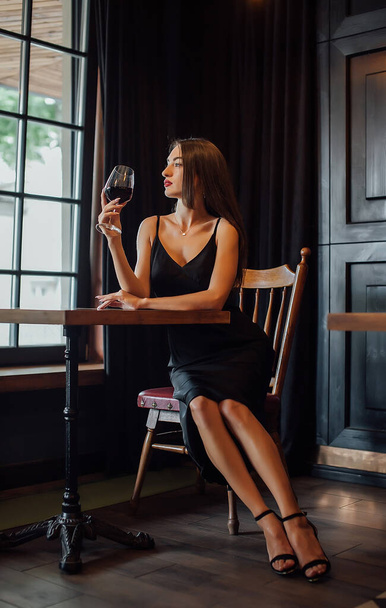 young elegant woman hold glass of red wine, indoor shot, selective focus - Foto, Imagem
