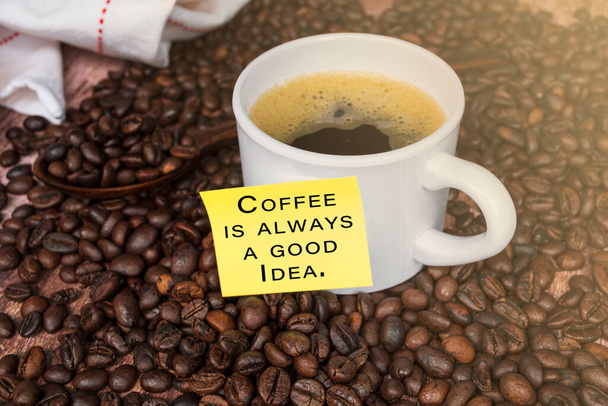 Motivationszitat auf gelbem Stick mit Kaffee auf Holzgrund - Kaffee ist immer eine gute Idee. - Foto, Bild