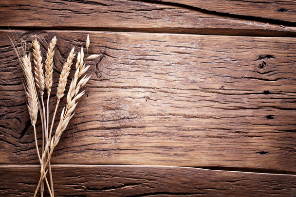 Ears of wheat on old wooden table. - 写真・画像