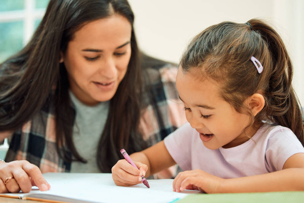 Cropped shot of an adorable little girl doing her homework with some help from her mom. - Foto, Imagen
