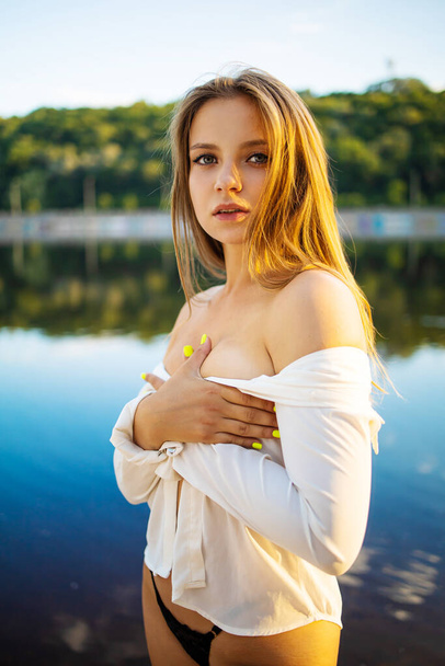 Beautiful young blond woman outdoors portrait near the lake in summer. - Photo, Image