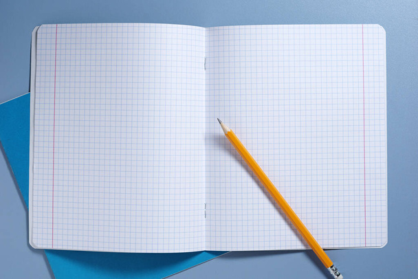 School notebooks and pencil on blue table, top view - Фото, изображение