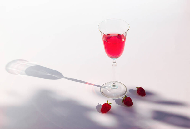 Δημιουργική καλοκαιρινή σύνθεση με φρέσκο κόκκινο χυμό φράουλας και σκιά από κλαδιά. Ελάχιστη έννοια του καλοκαιρινού ποτού. - Φωτογραφία, εικόνα
