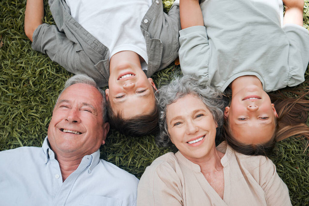 Shot of a senior couple lying outside with their two grandchildren. - Foto, imagen