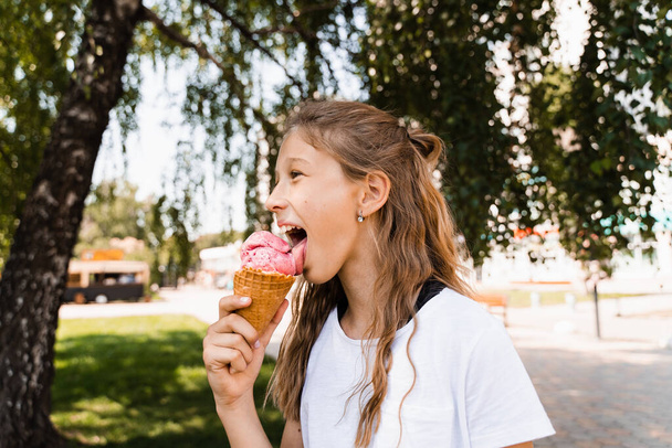 Funny child girl eating ice cream cone in waffle cup. Creative advert for ice cream stand and shop - Photo, Image