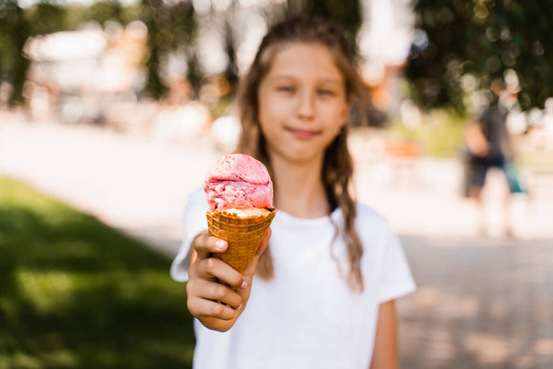 Ice cream cone close-up with child girl on background. Summer sweets food. Creative advert for ice cream stand and shop - Fotografie, Obrázek
