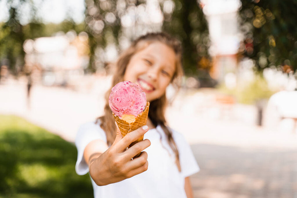 Ice cream cone close-up with child girl on background. Summer sweets food. Creative advert for ice cream stand and shop - Fotoğraf, Görsel