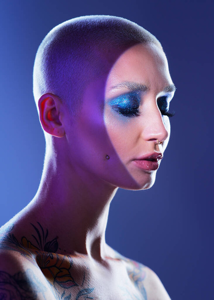 Mavi arka planda, kenar makyajı yapan çekici bir genç kadının stüdyo fotoğrafı.. - Fotoğraf, Görsel