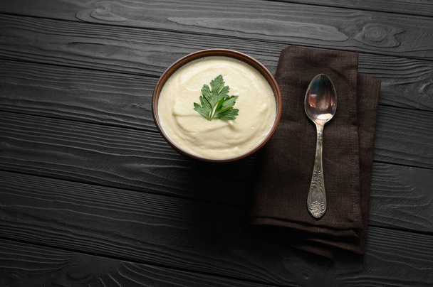Cream of cauliflower soup on a dark wooden background. - Фото, изображение