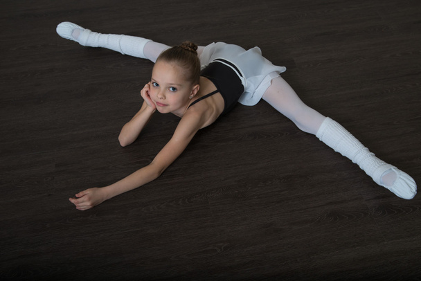 A little adorable young ballerina doing stretching exercises on - Zdjęcie, obraz