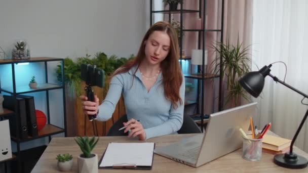 Young woman businesswoman blogger using smartphone shooting video call for social media posing smiling sitting at table working from home office. Girl freelancer study, e-learning, remote job online - Footage, Video