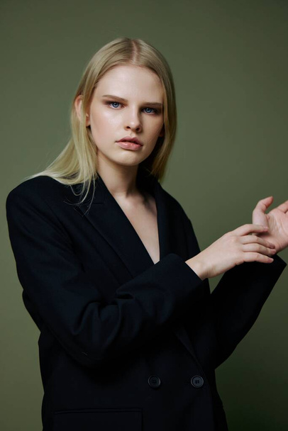 Portret van een prachtig elegant meisje in een zwart pak dat professioneel poseert op een groene achtergrond in de studio. Het concept van reclame voor designermerken. Hoge kwaliteit foto - Foto, afbeelding