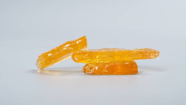 cannabis wax with high thc on gray background, pieces of golden clean marijuana concentrate. - Photo, image