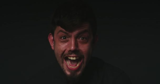 Gesichtsporträt eines schizophrenen Patienten vor blinkendem schwarzen Hintergrund im Studio mit Kopierraum. Geisteskranker, wütender, verrückter oder psychisch kranker Mann, der schreit und schreit, während er an Schizophrenie leidet. - Filmmaterial, Video