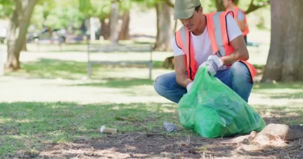 Male volunteer cleaning a park in his community. Responsible council workers, activists and volunteers collecting garbage and litter to reduce pollution for a sustainable, clean and safe environment. - Video