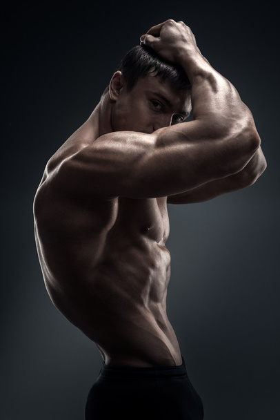 Handsome muscular bodybuilder posing over black background - Photo, Image