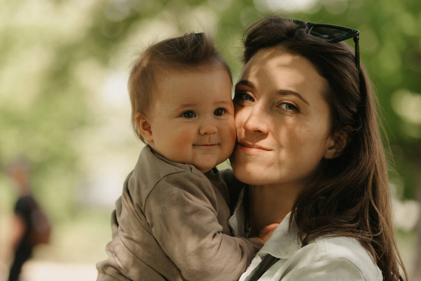 Una giovane madre tiene tra le braccia sua figlia di 7 mesi nel parco. Una mamma si sta godendo la figlia neonata nel bosco. - Foto, immagini