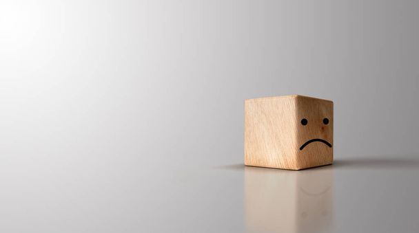 Triste face sur cubes en bois sur fond gris pour des idées de sélection négatives. - Photo, image