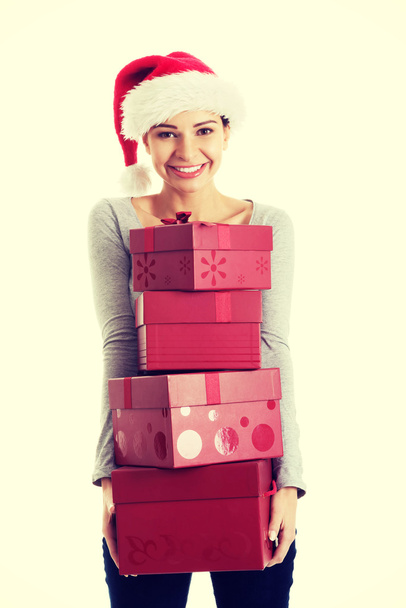 Beautifull woman in santa hat holding presents. - Zdjęcie, obraz