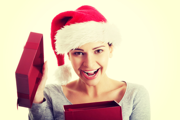 Beautiful woman in santa hat and opening present. - Foto, afbeelding