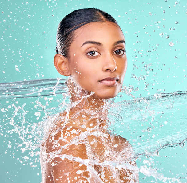 een aantrekkelijke jonge vrouw douchen tegen een blauwe achtergrond. - Foto, afbeelding