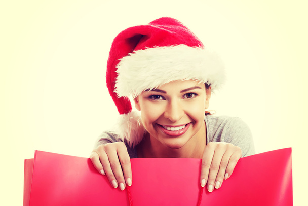 Beautiful woman wearing santa hat, holding shopping bag. - Photo, image