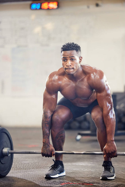 мускулистый молодой человек, тренирующийся с штангой в спортзале. - Фото, изображение